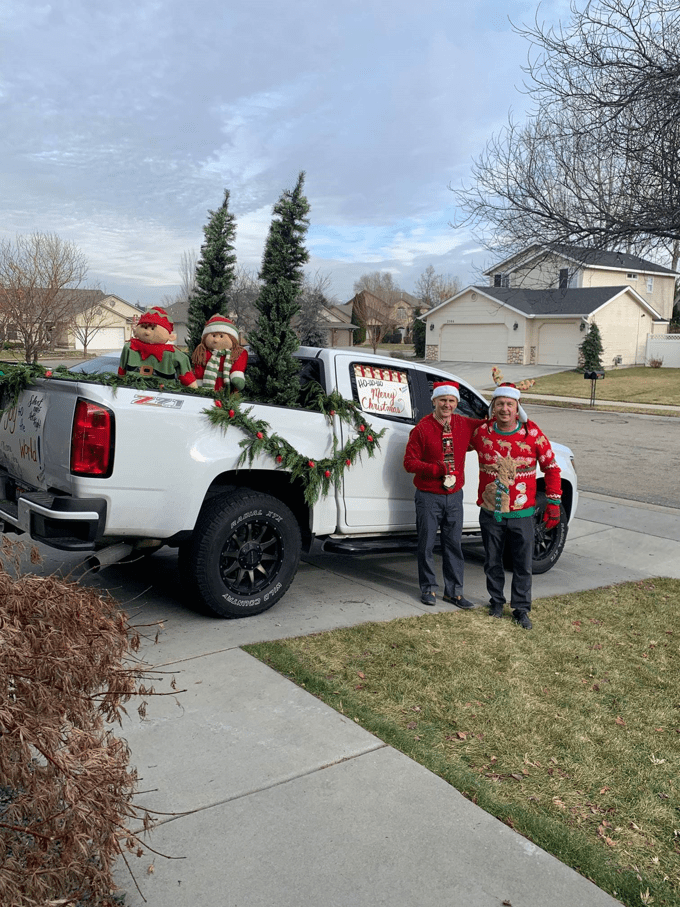 people dressed up for christmas next to decorated truck